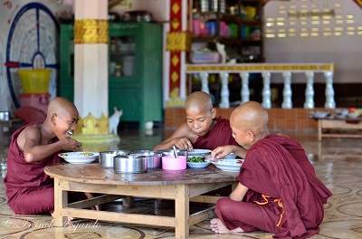 Monks eating on a low table in a Burmese temple