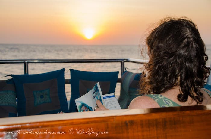 Reading a book on the sofa on the M Smiling Seahorse at sunset